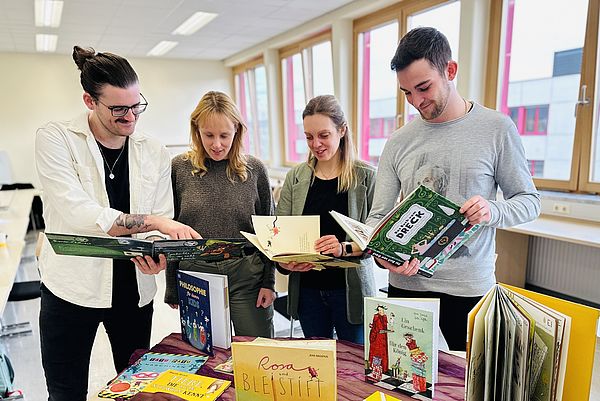 weibliche und männliche Studierenden halten Bücher in der Hand und schauen gemeinsam hinein