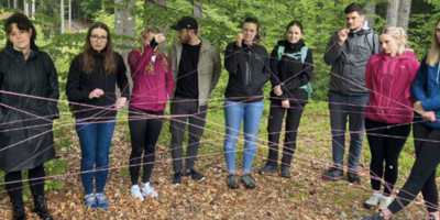Studierende stehen im Wald und bilden mit Schnüren ein Netz