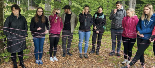 Studierende stehen im Wald und bilden mit Schnüren ein Netz