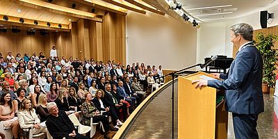 Rektor vor Stehpult im Festsaal stehend redet